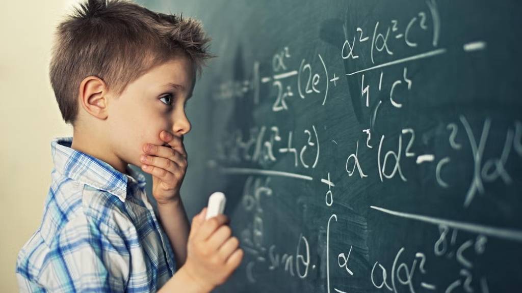 kid solving a problem on the board while holding a chalk
